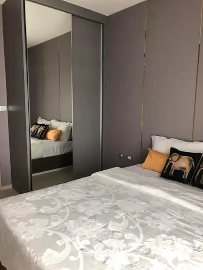 Modern bedroom with mirrored closet and stylish decor in a contemporary apartment.