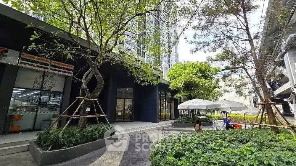 Modern building exterior with lush greenery and outdoor seating area.