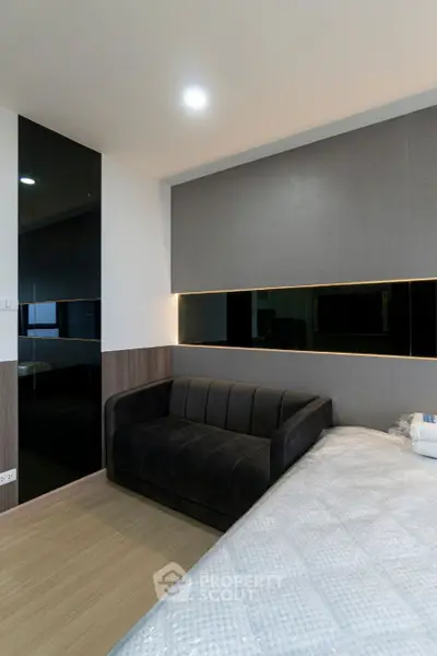 Modern bedroom with sleek design and cozy sofa, perfect for relaxation.