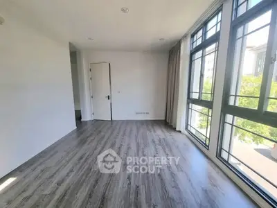 Spacious empty room with large windows and wood flooring, ideal for customization.