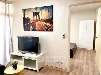 Cozy living room with modern decor and TV, leading to a minimalist bedroom.