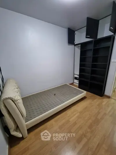 Compact bedroom with wooden flooring and built-in storage shelves.