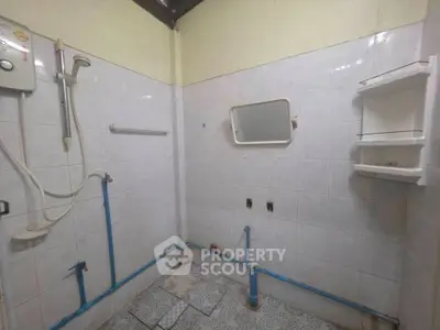 Spacious bathroom with tiled walls and shower setup, ideal for renovation opportunities.