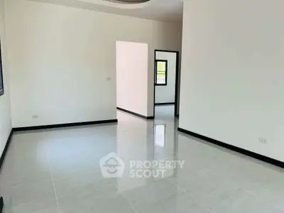 Spacious empty room with glossy tiled floors and white walls, ideal for customization.