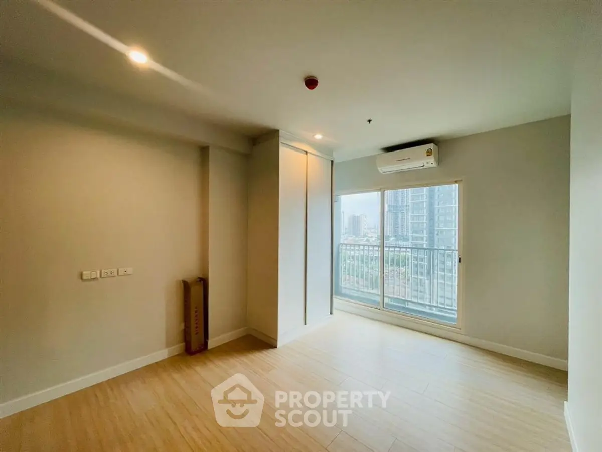 Spacious empty room with large window and city view, perfect for customization.
