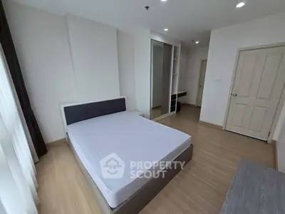 Spacious bedroom with modern design and ample natural light, featuring a comfortable bed and sleek storage solutions.
