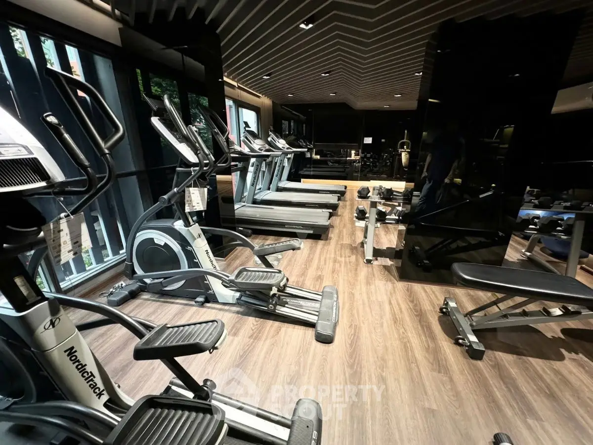 Luxurious gym with modern equipment and sleek design in upscale residential building.