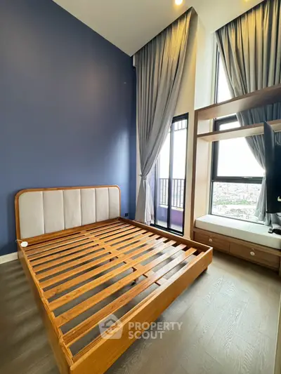 Spacious bedroom with high ceilings and large windows offering a stunning view, featuring a modern wooden bed frame.