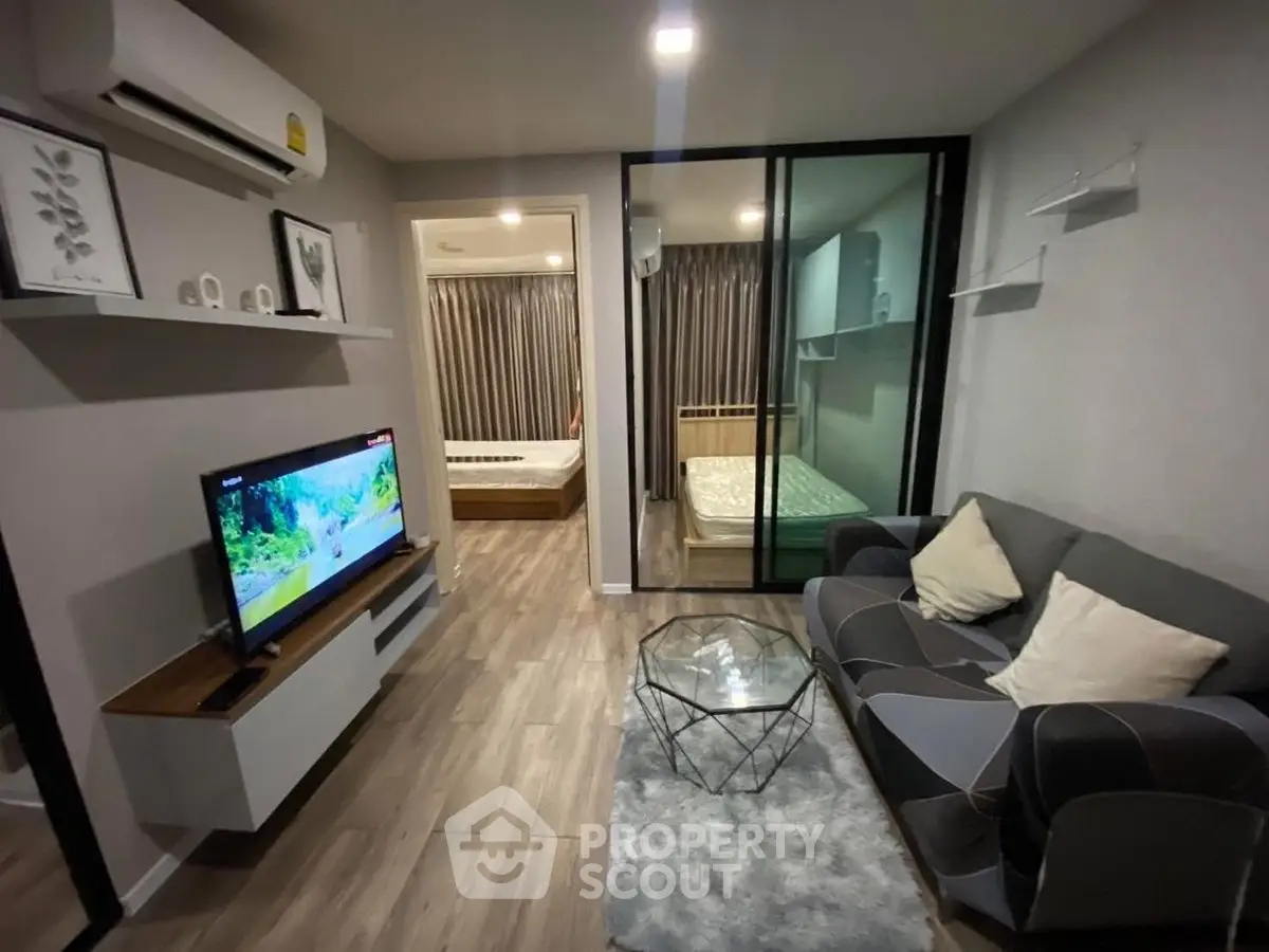 Modern living room with sleek furniture and open view to bedroom