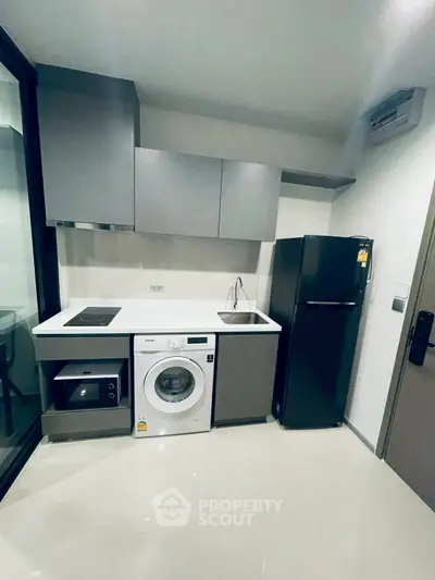 Modern kitchen with sleek appliances including washing machine and fridge, compact and stylish design.