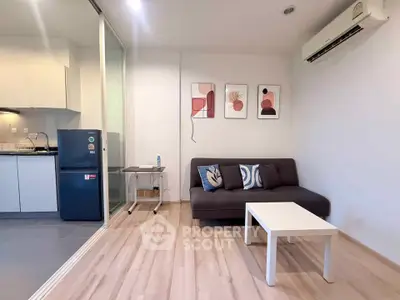 Modern living room with stylish decor and open kitchen layout, featuring a cozy sofa and sleek appliances.