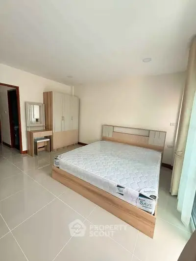 Spacious bedroom with modern furniture and large window for natural light.