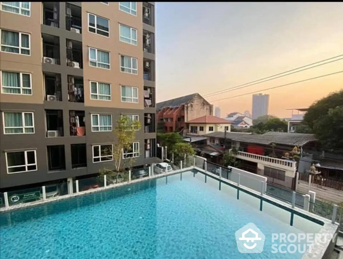 Modern apartment building with rooftop pool and city view at sunset