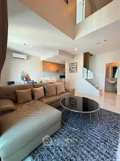 Spacious modern living room with open kitchen and stylish decor in a duplex apartment.