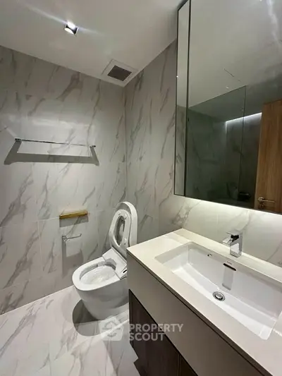 Modern bathroom with sleek fixtures and marble tiles, featuring a spacious vanity and elegant lighting.