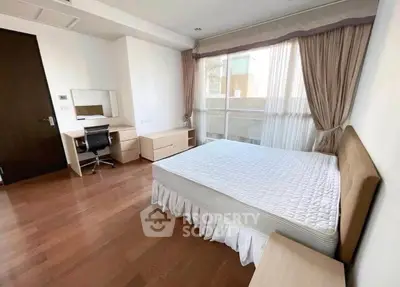 Spacious bedroom with hardwood floors and large window in modern apartment