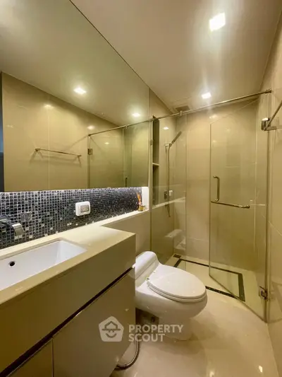 Modern bathroom with glass shower and sleek vanity in luxury apartment.