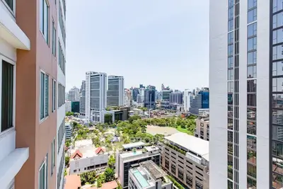 Stunning cityscape view from high-rise building balcony, showcasing urban skyline and lush greenery.