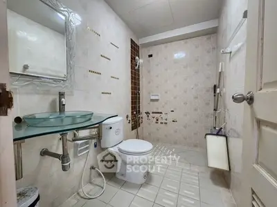 Modern bathroom with glass sink and tiled walls in a stylish real estate property.
