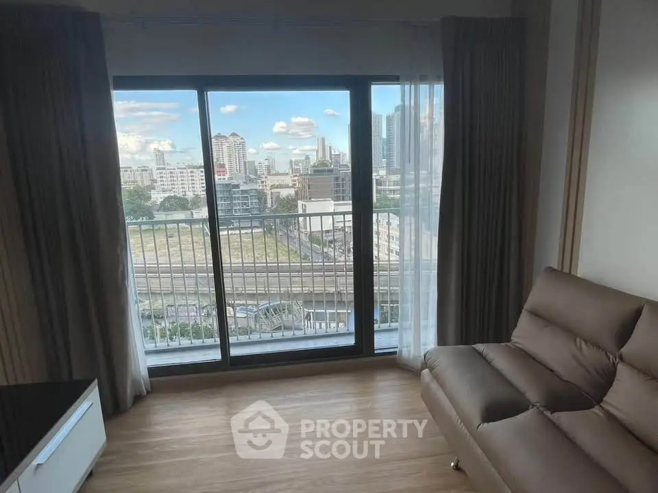 Modern living room with large window offering stunning city view and cozy seating area.