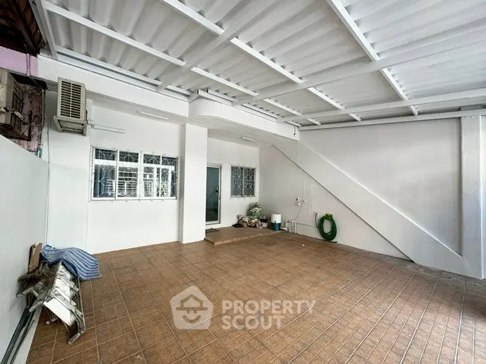 Spacious covered parking area with tiled flooring and air conditioning unit.