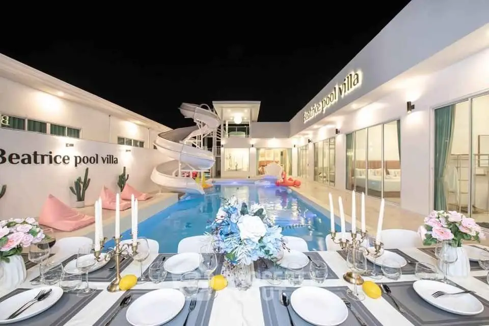 Luxurious pool villa with elegant dining setup and spiral slide, perfect for entertaining.