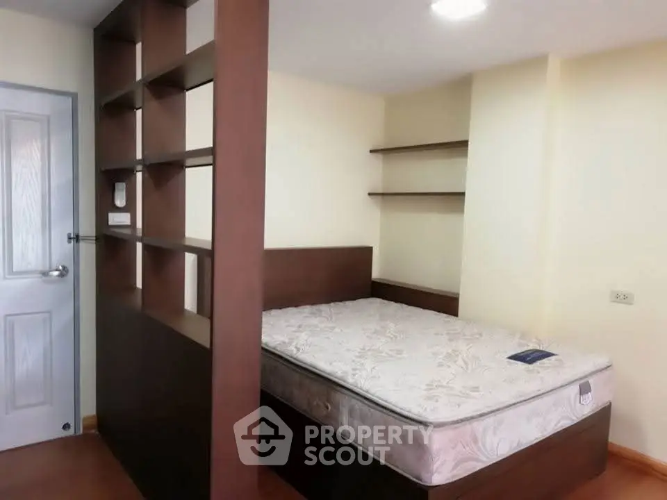 Cozy bedroom with built-in shelves and comfortable mattress in modern apartment.
