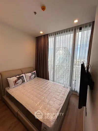 Modern bedroom with large window and city view, featuring a comfortable bed and wall-mounted TV.