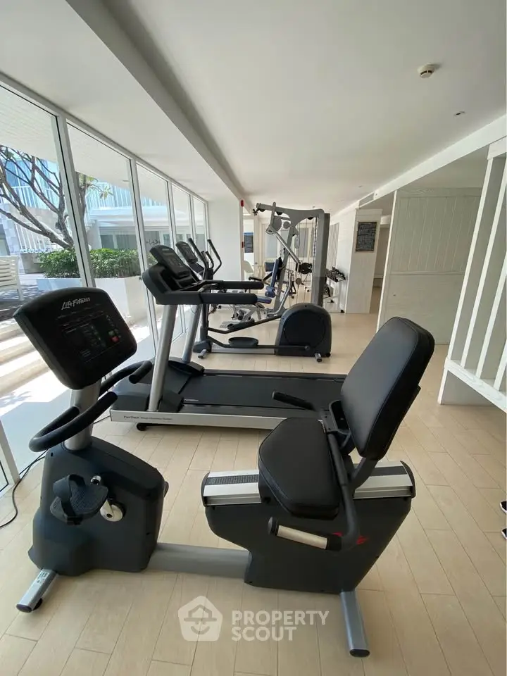 Modern gym with state-of-the-art equipment and large windows for natural light.
