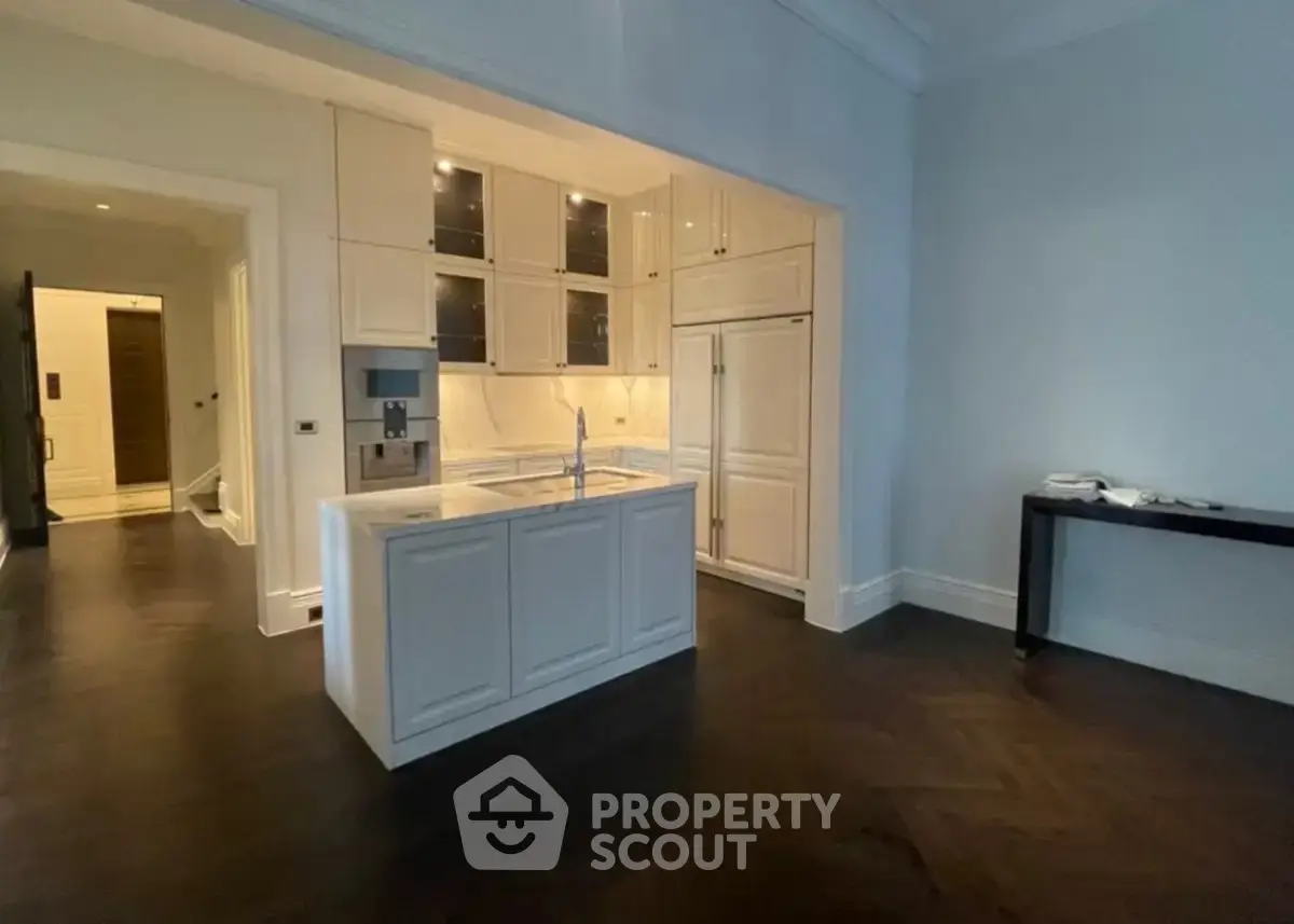 Elegant kitchen with white cabinetry and dark wood flooring in a modern apartment.