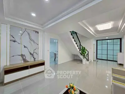 Spacious modern living room with elegant marble accents and sleek staircase.