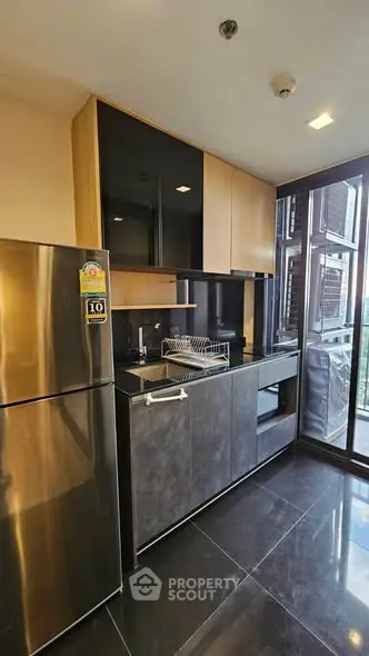 Modern kitchen with sleek design, featuring stainless steel appliances and large windows for natural light.