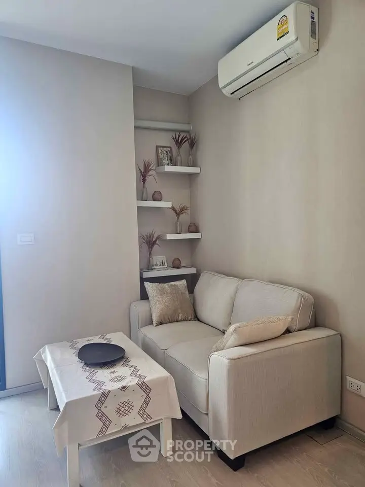 Cozy living room with modern sofa, air conditioning, and decorative shelves in a stylish apartment.