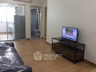 Modern living room with TV and sleek furniture, adjacent to kitchen and bathroom.
