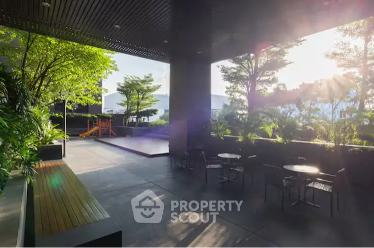 Modern outdoor patio with lush greenery and seating area in a residential complex.