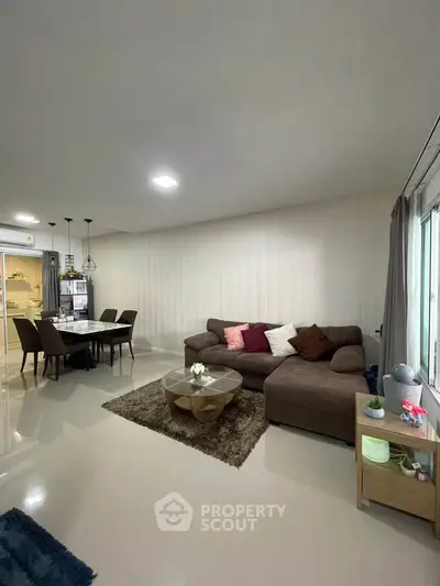 Modern living room with cozy sectional sofa and dining area in open layout apartment.
