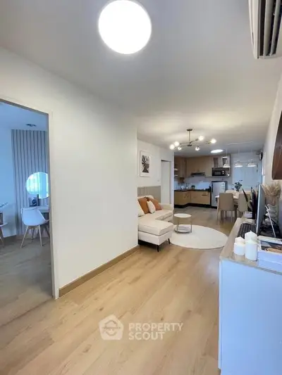 Modern open-plan living room with stylish kitchen and dining area, featuring elegant lighting and wooden flooring.