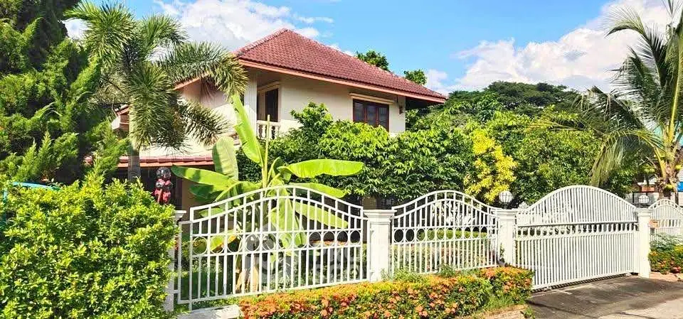 Charming tropical house with lush garden and elegant white fence