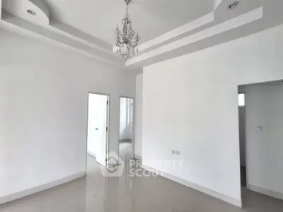 Spacious white-walled room with elegant chandelier and modern ceiling design