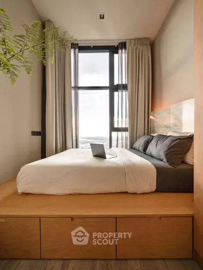 Modern bedroom with elevated bed and large window offering stunning city view.