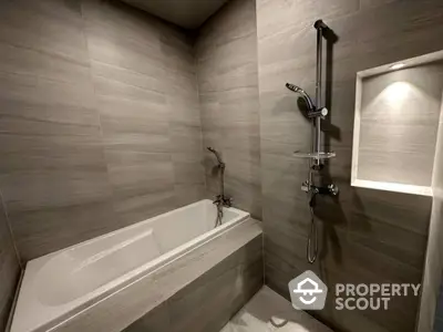 Modern bathroom with sleek gray tiles and built-in bathtub