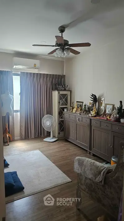 Cozy living room with wooden flooring, ceiling fan, and elegant furniture, perfect for relaxation.