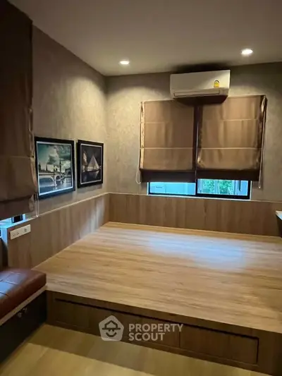 Cozy bedroom with wooden platform bed and air conditioning, featuring modern decor and natural light.