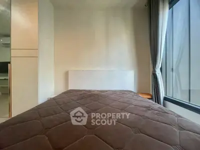 Cozy bedroom with large window and modern decor, perfect for relaxation and comfort.