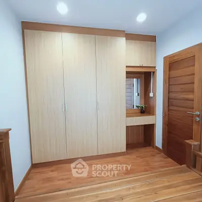 Spacious wooden wardrobe with mirror in modern bedroom