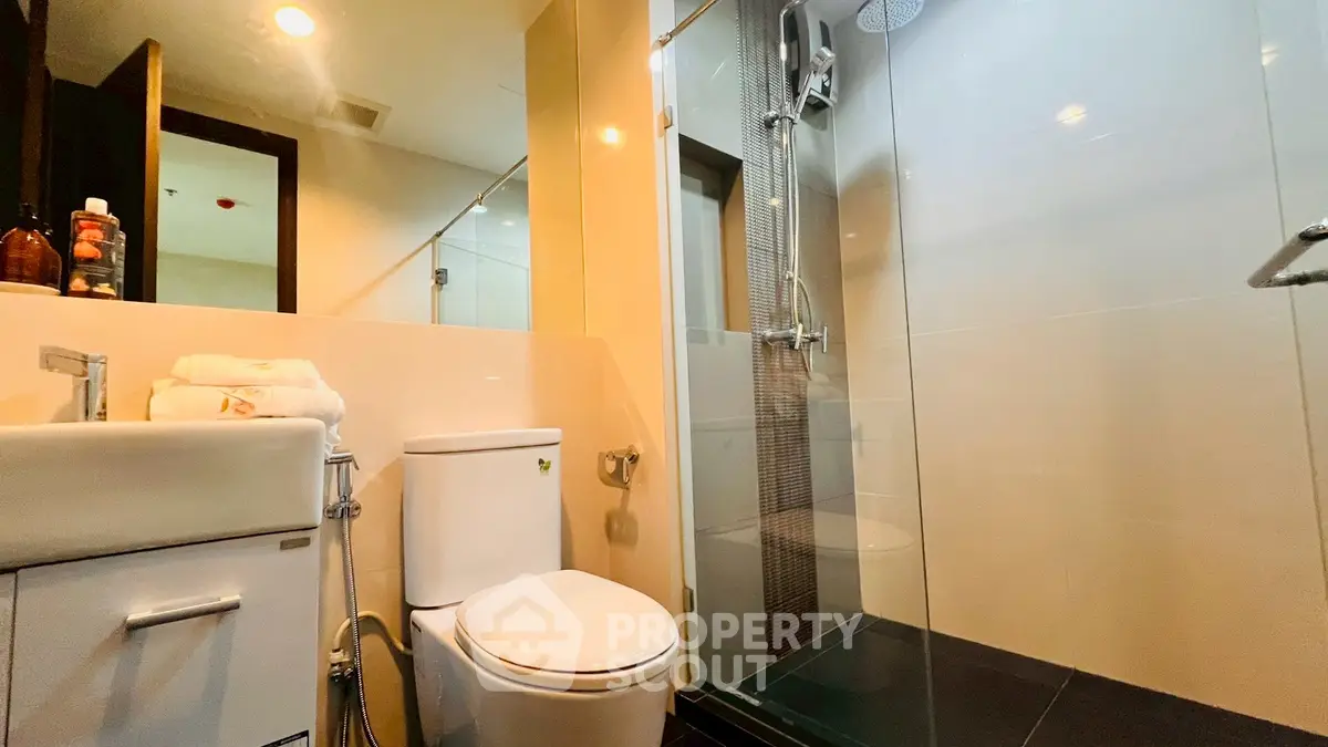 Modern bathroom with glass shower and sleek fixtures in contemporary apartment.
