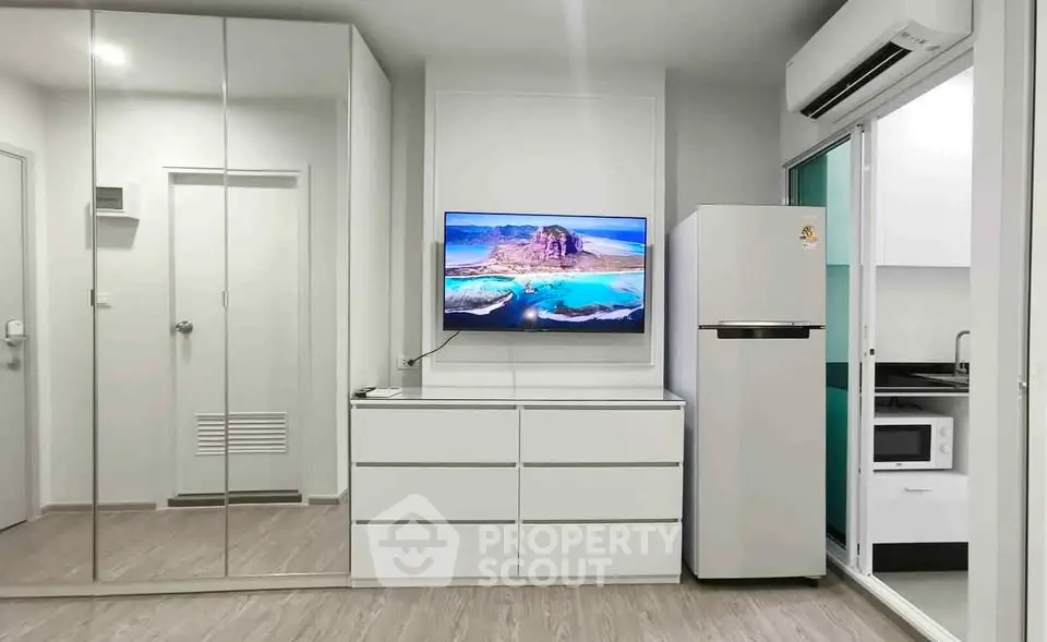 Modern apartment interior with mirrored wardrobe, TV, and sleek kitchen appliances.