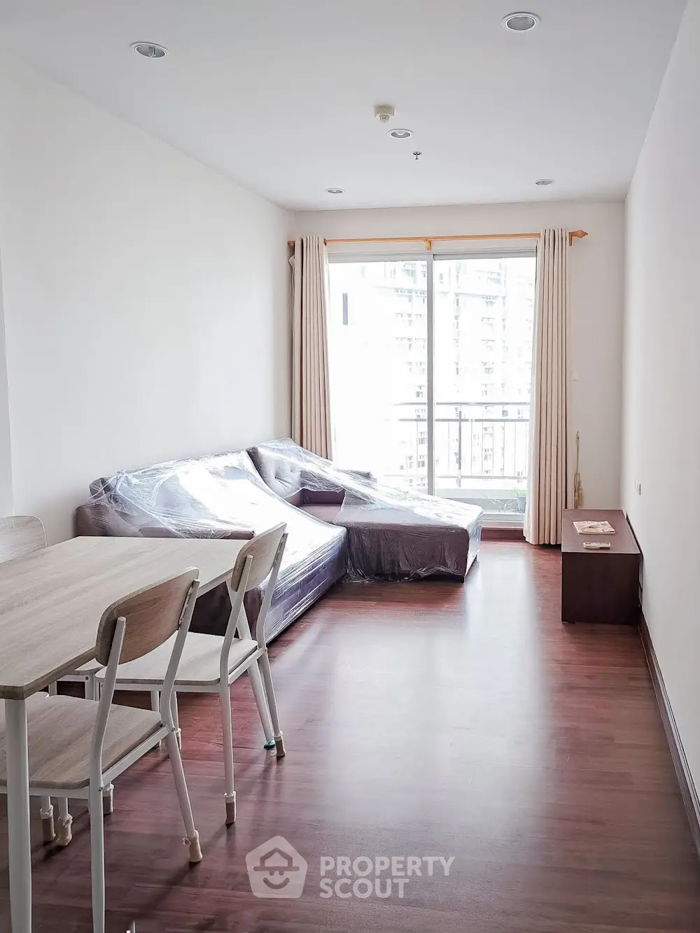 Spacious living room with large windows and modern furniture in a high-rise apartment.