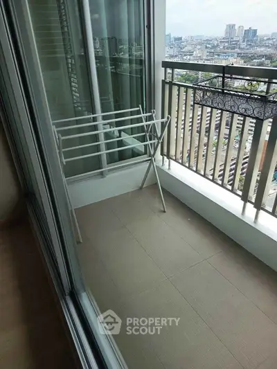 Modern apartment balcony with city view and drying rack, perfect for urban living.