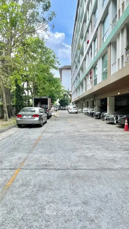 Modern apartment building with parking area and lush greenery, ideal urban living.